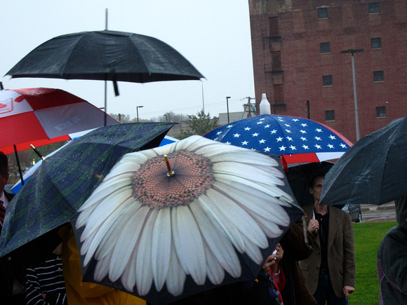 Guests with umbrellas await the unveiling of “Convergence of Purpose” during the dedication October 23, 2010.