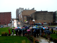 Guests with umbrellas gather around “Convergence of Purpose” during the dedication October 23, 2010.