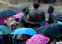The figures in the statuary grouping appear amid the umbrellas of the audience after the unveiling of the work October 23, 2010.