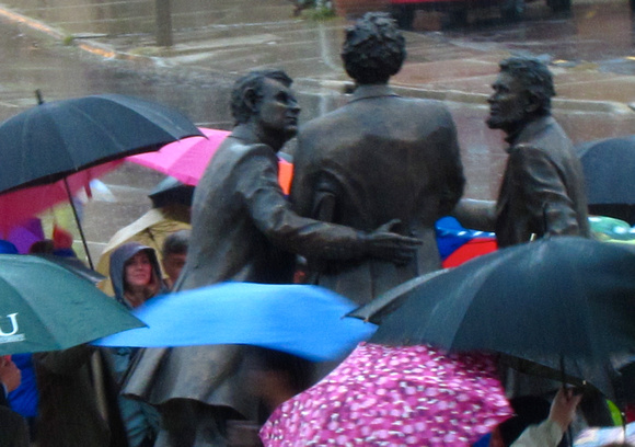 The figures in the statuary grouping appear amid the umbrellas of the audience after the unveiling of the work October 23, 2010.
